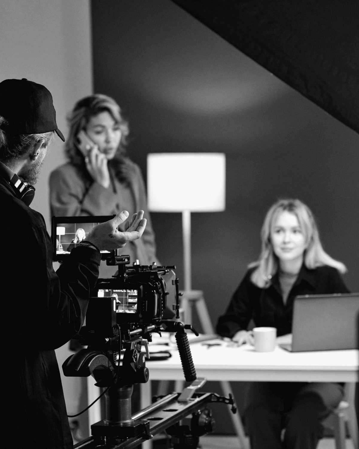 Un'intervista sul set: l'operatore alla camera e la protagonista seduta alla scrivania